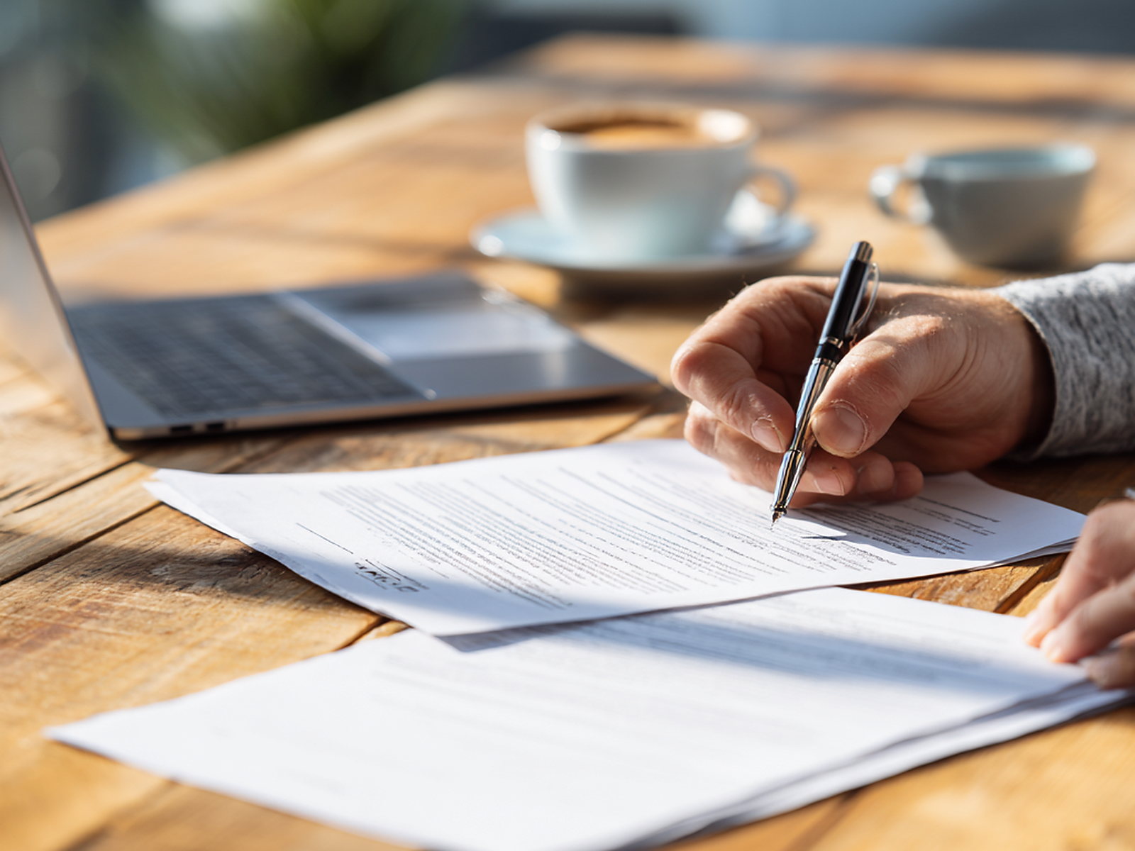 Hands taking notes beside a coffee cup